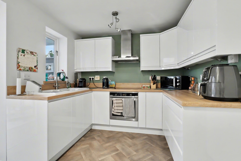 Spacious kitchen diner with electric oven and hob, flowing seamlessly into the light-filled conservatory beyond