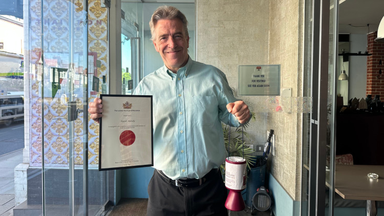 Mark Hardy, Thai Upon Thames front-of-house manager holding up his certificate of recognition from the Hounslow Mayor (credit: Riana McConochie).