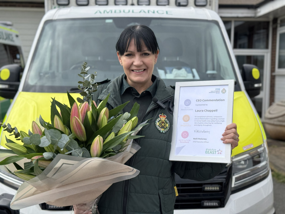 Emergency Care Assistant Laura Chappell stands proudly with her commendation and a bouquet of flowers.
