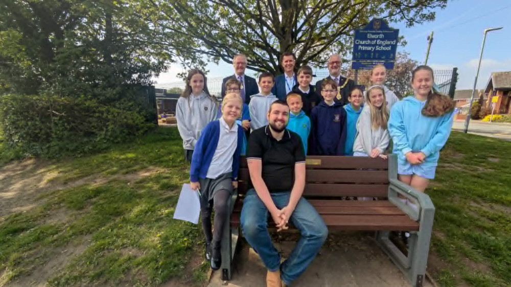 Cllr Simon Richards takes a seat on the bench surrounded by those who made it happen. (Photo: Nub News) 