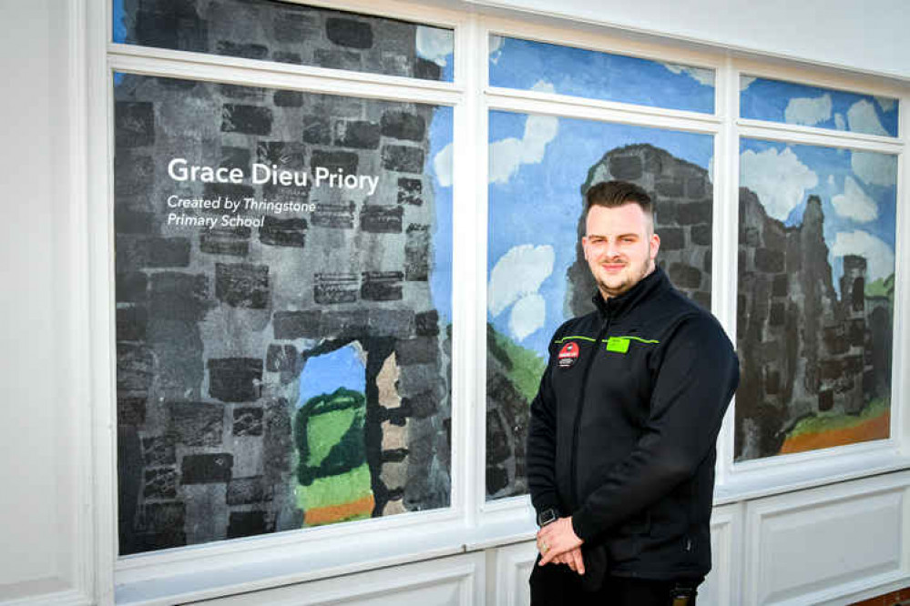 Central England Co-op Thringstone Store Manager Kurtis Redburn next to the artwork produced by Thringstone Primary School for the store