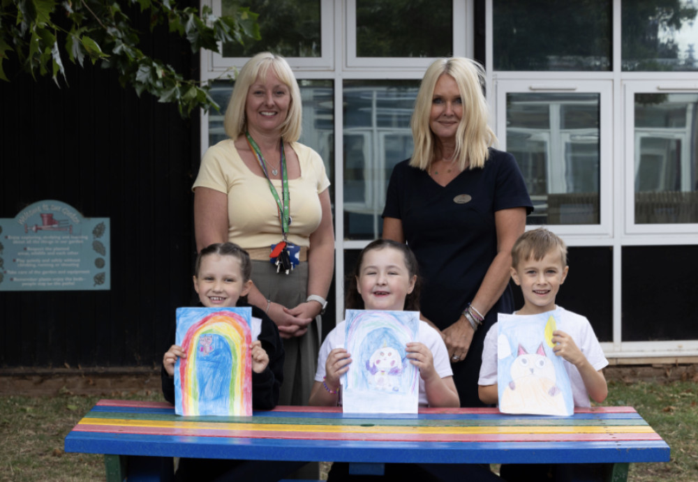 •	Whitnash Primary School Headteacher Donna Ellison (left) and Bellway Sales Advisor Louise Powell with pupils Elsie, Esme and Jacob proudly holding up their winning artwork (image supplied) 