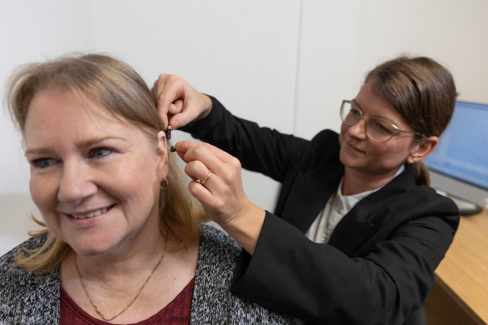 Audiologist Ele Kendall, fitting a patient with a hearing aid