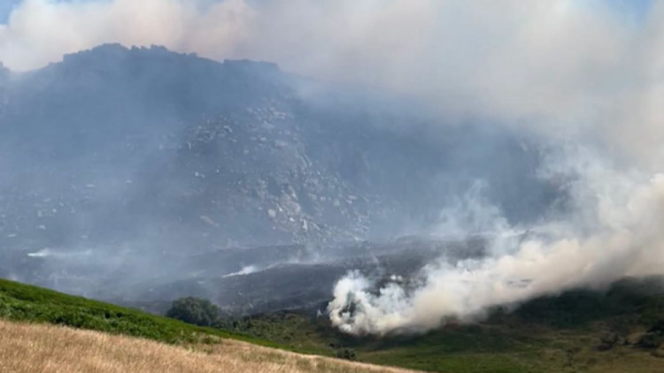 Four people have been charged with 'arson with recklessness as to whether life was endangered' in relation to the Dovestones fire in July (Image - GMFRS)