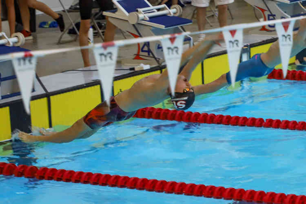 A Street swimmer takes off in the backstroke event