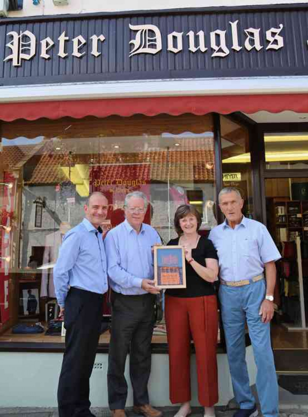 Philip Welch presents the commemorative plaque to Tracey Sage watched by her staff Peter Bowers and Richard Jones