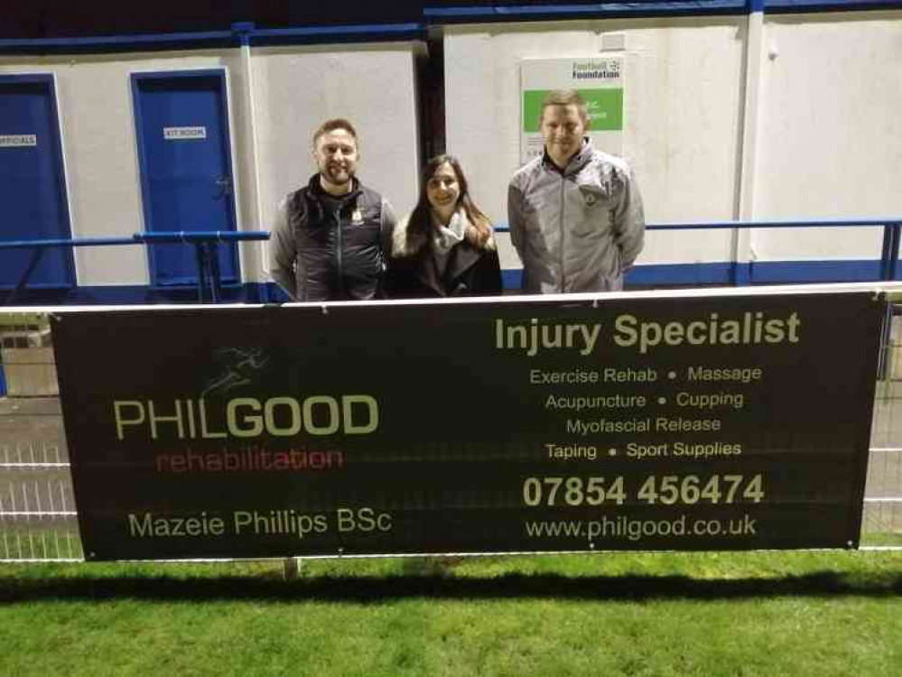 Mazeie Phillips, of Philgood Rehabilitation, with her new sponsorship board at the Athletic Ground, with Wells City joint managers Nathan Truckle and Tom Clifford-Jones